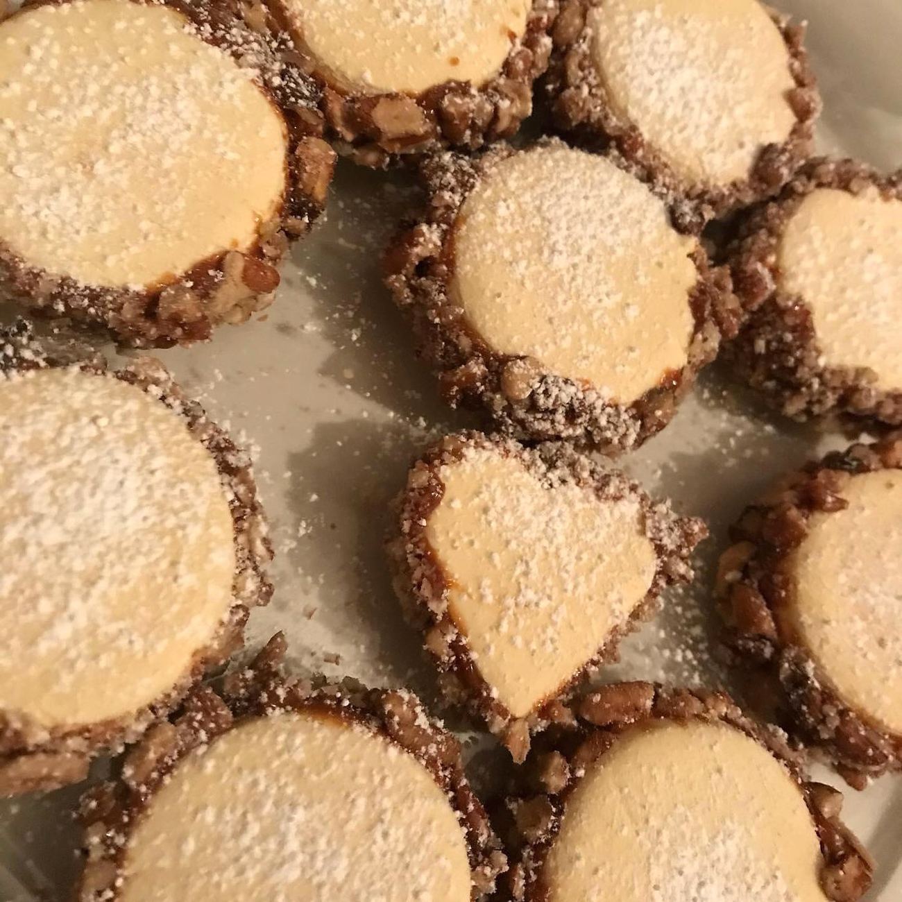 Alfajores de nuez vistos desde arriba, con azúcar glass y borde de nuez picada